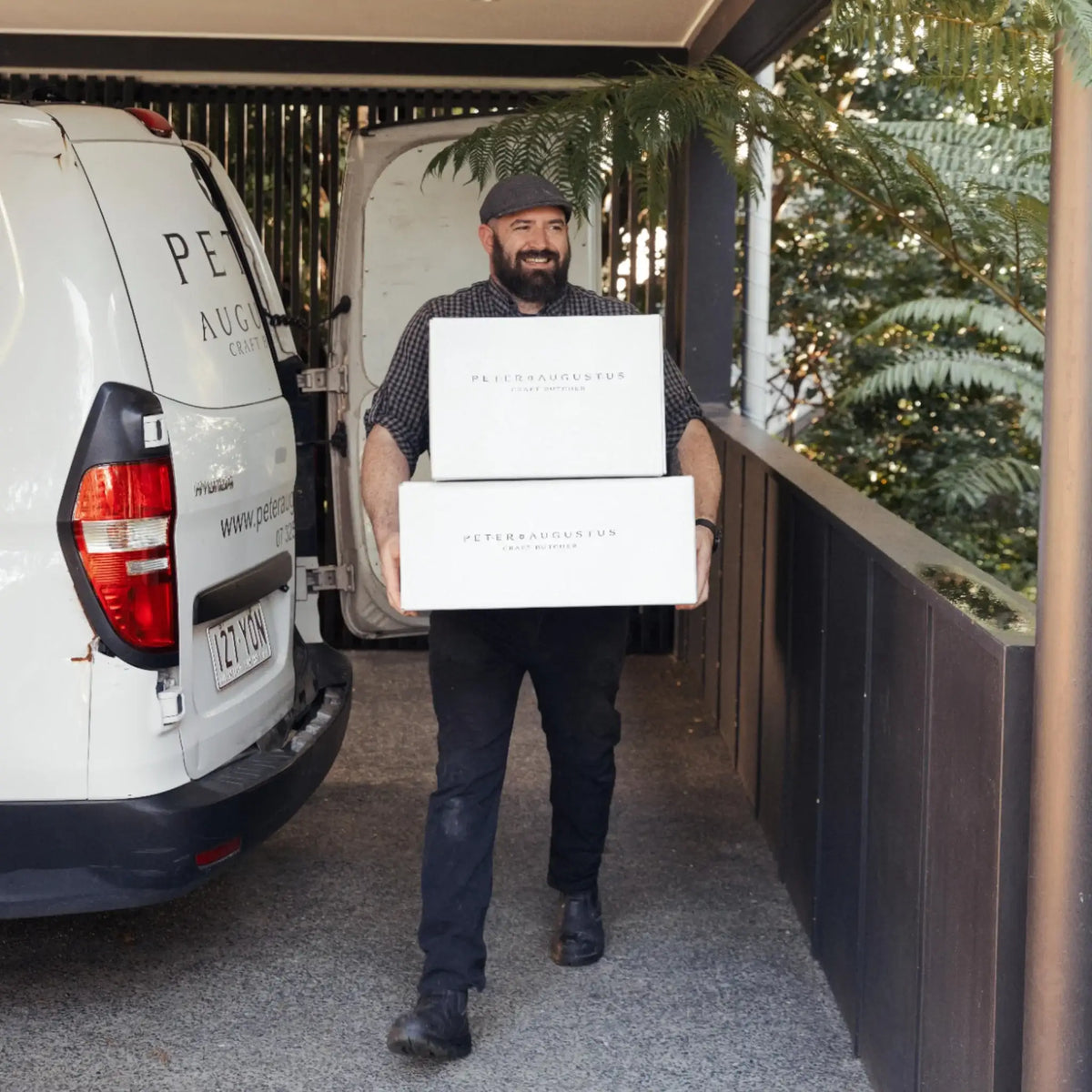 Delivery man carrying Peter Augustus Craft Butcher beef boxes from branded van outdoors