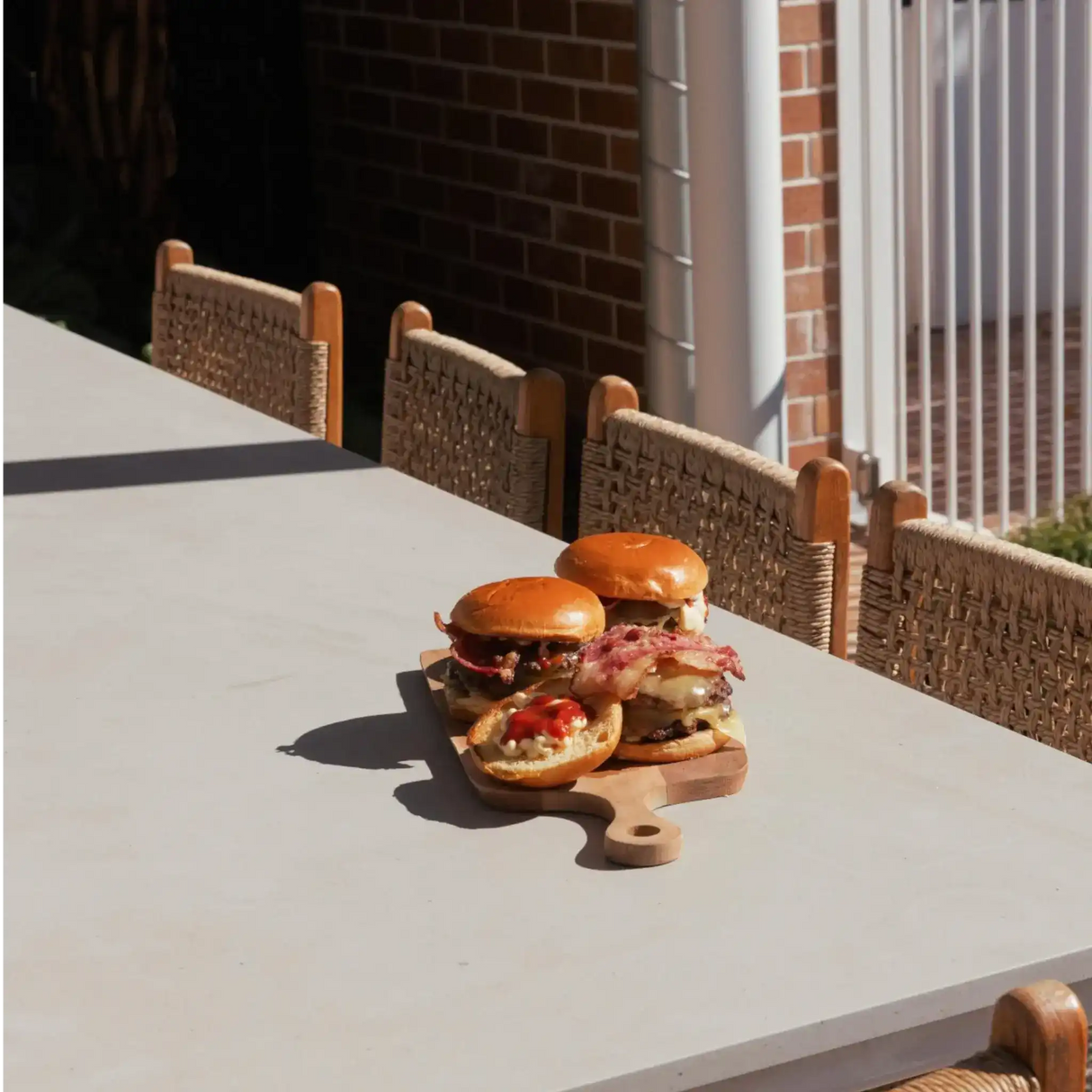 Juicy beef burgers with bacon and cheese on a wooden board, perfect for outdoor dining