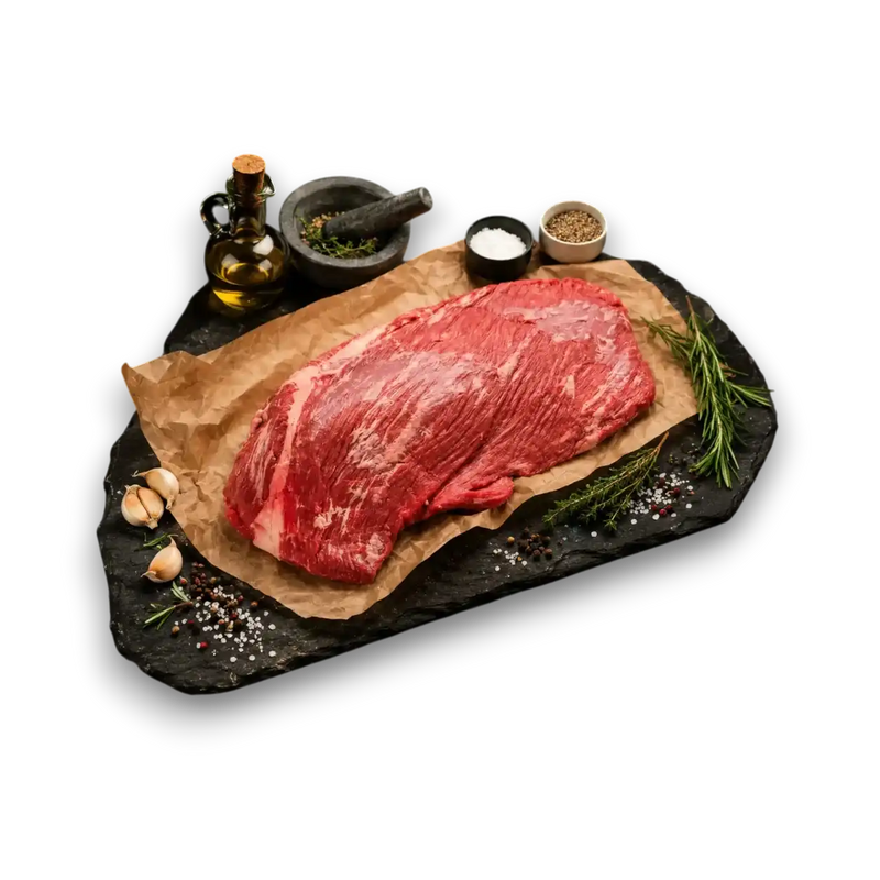 Fresh grass-fed beef steak on slate with rosemary, garlic, salt, pepper, and olive oil for cooking