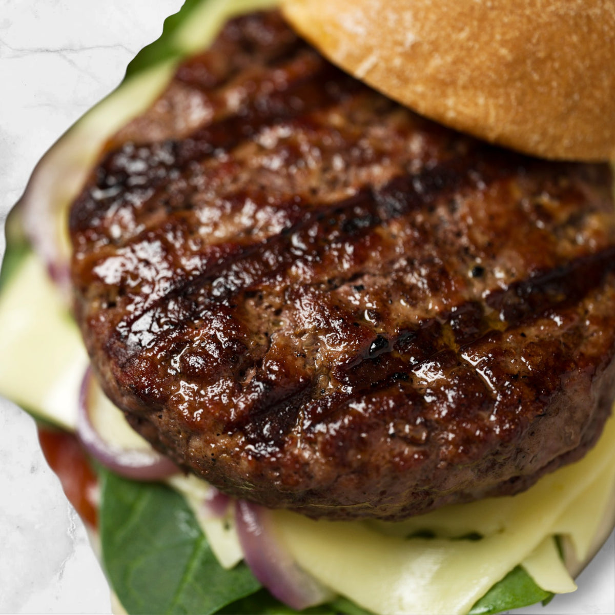 Juicy grilled Wagyu beef burger patty on artisan bun with cheese, onion and greens