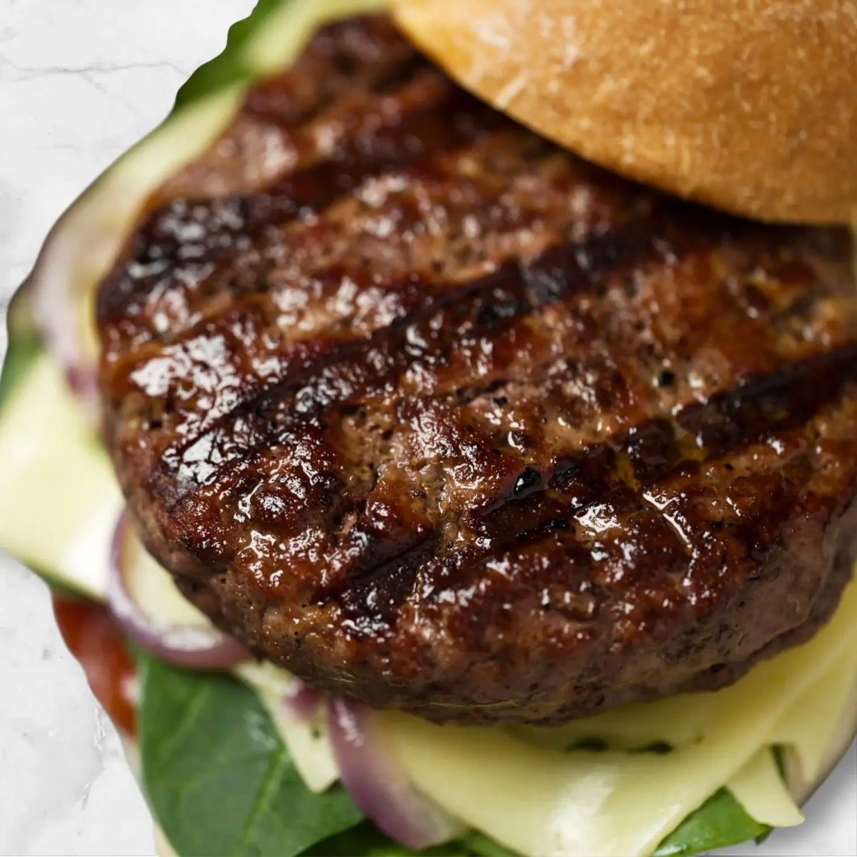 Juicy grilled Wagyu beef burger patty on artisan bun with cheese, onion and greens