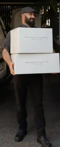 Man holding two boxes with 'Vermont Creamery' branding in a vehicle.
