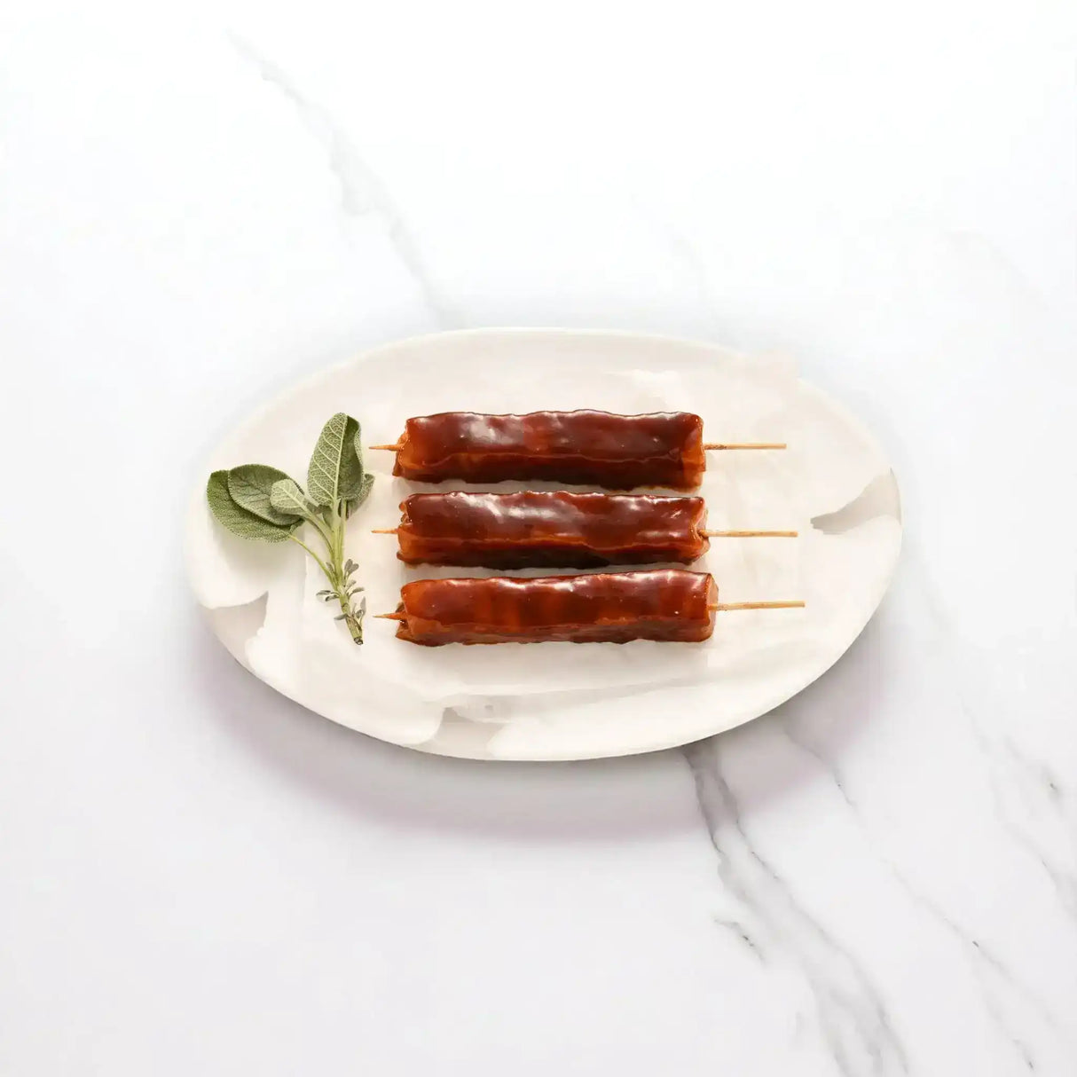 Honey soy chicken kebabs with sticky BBQ glaze on skewers, served on a white plate with fresh herbs.