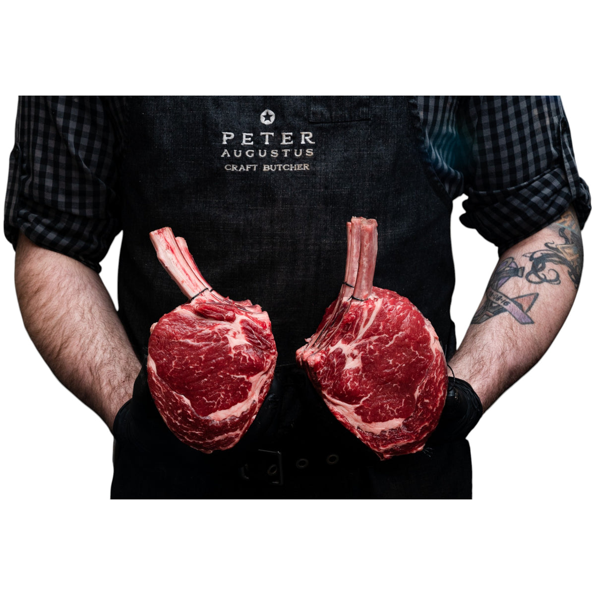Butcher holding two premium Pure Angus standing rib roasts from Peter Augustus Craft Butcher