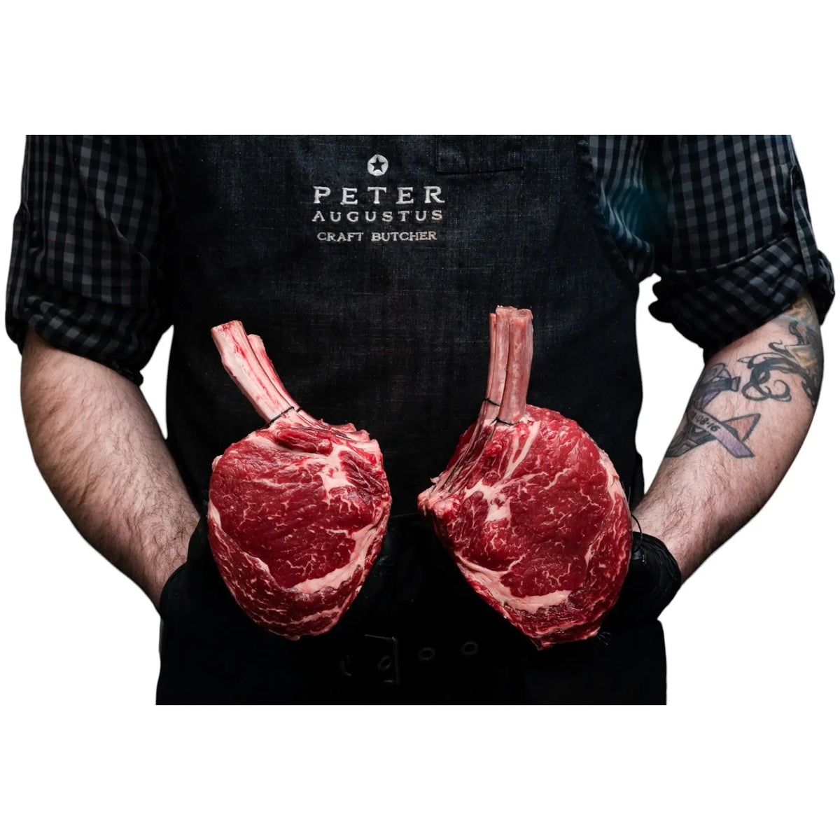 Butcher holding two premium Pure Angus standing rib roasts from Peter Augustus Craft Butcher