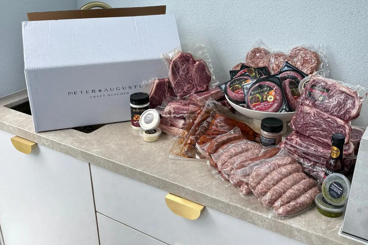 Assorted meats and condiments on a kitchen counter with a branded box.