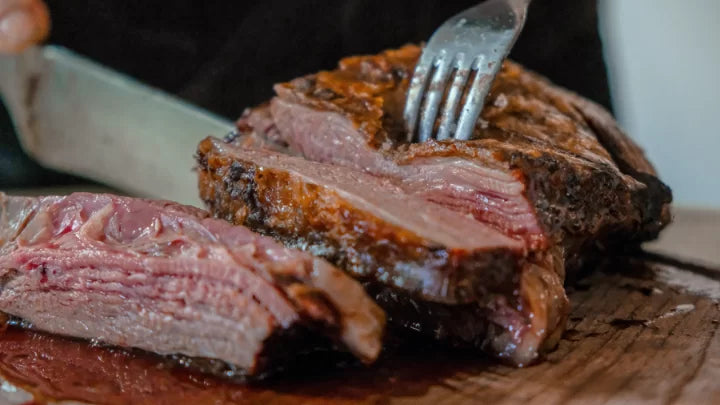 Smoked beef brisket sliced on a wooden board with bark and smoke ring, BBQ pitmaster style