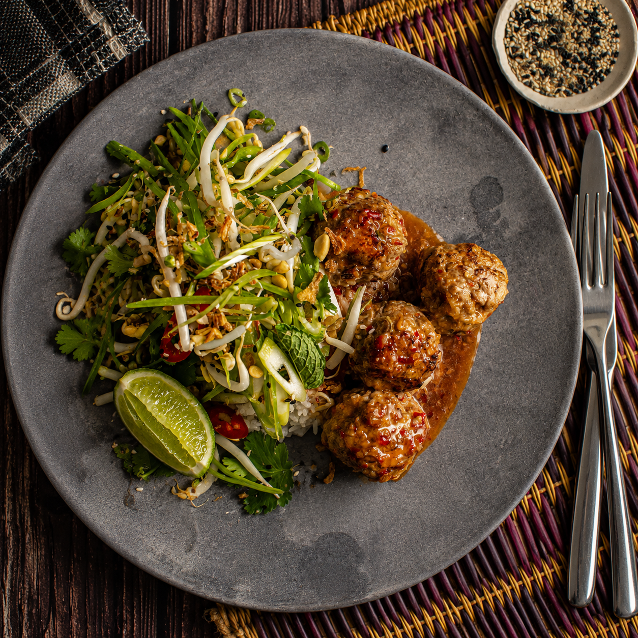 Australian beef meatballs with sweet chili sauce, rice, fresh herbs, and lime on a plate