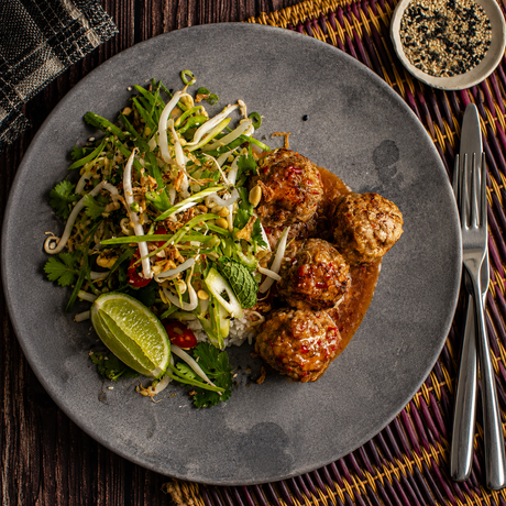 Australian beef meatballs with sweet chili sauce, rice, fresh herbs, and lime on a plate
