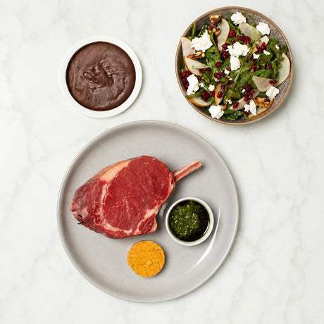 Raw Tomahawk steak with herb sauce, compound butter, chocolate dessert, and gourmet salad