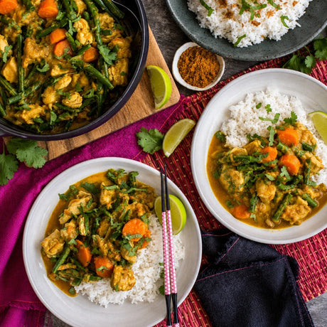 Australian beef curry with green beans, carrots, and rice, garnished with fresh cilantro and lime