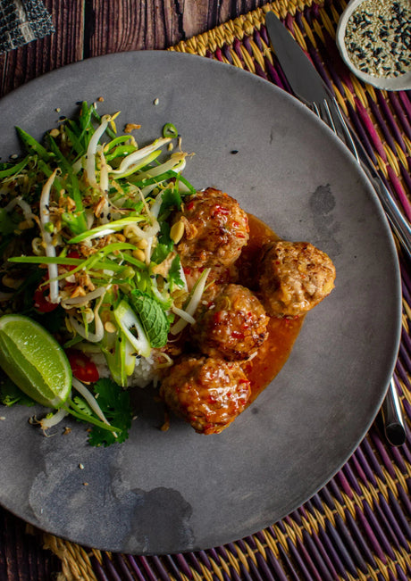 Australian beef meatballs with sweet chili sauce, rice, fresh herbs, and lime on a plate