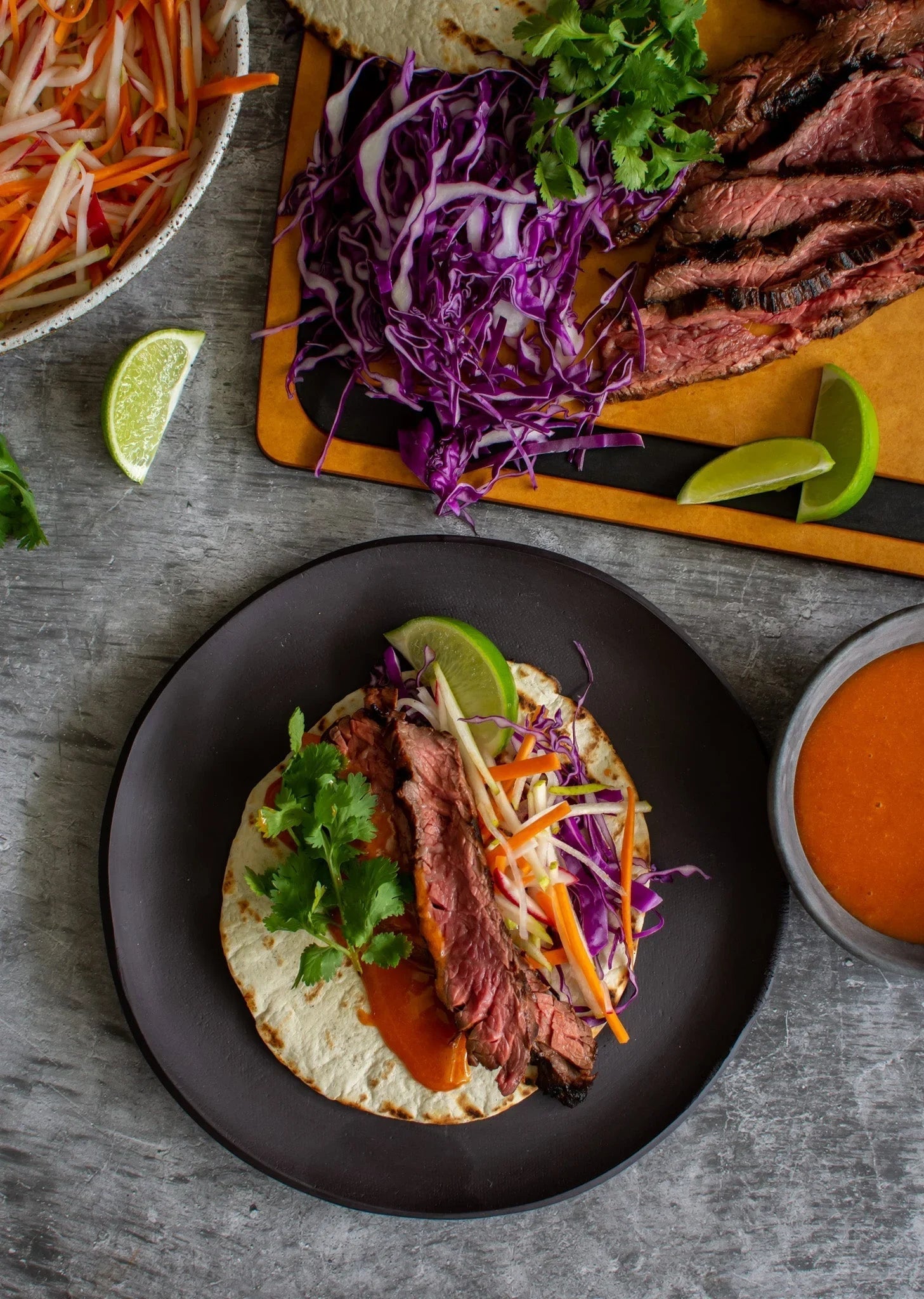 Sliced Australian beef taco with purple cabbage, carrots, coriander, and lime on a tortilla