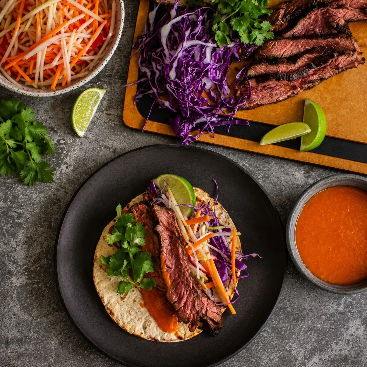 Sliced Australian beef taco with purple cabbage, carrots, coriander, and lime on a tortilla