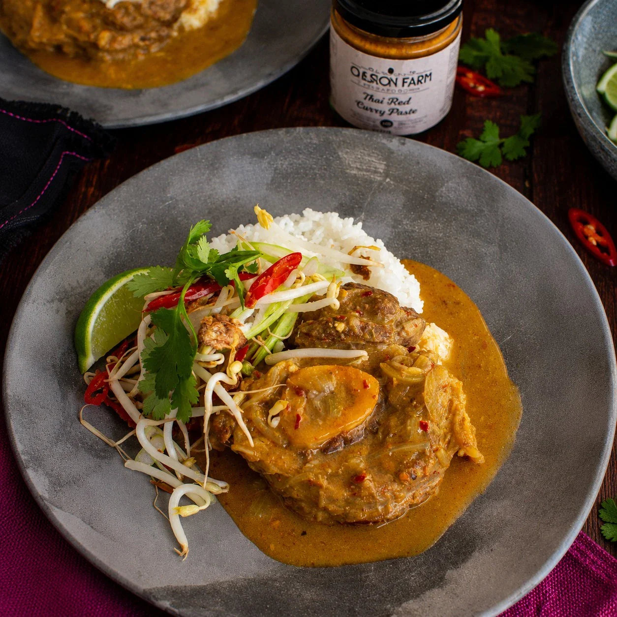 Australian beef curry with rice, fresh herbs, and bean sprouts on a gray plate