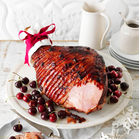 Glazed roast ham garnished with cherries, presented on a white plate, Peter Augustus
