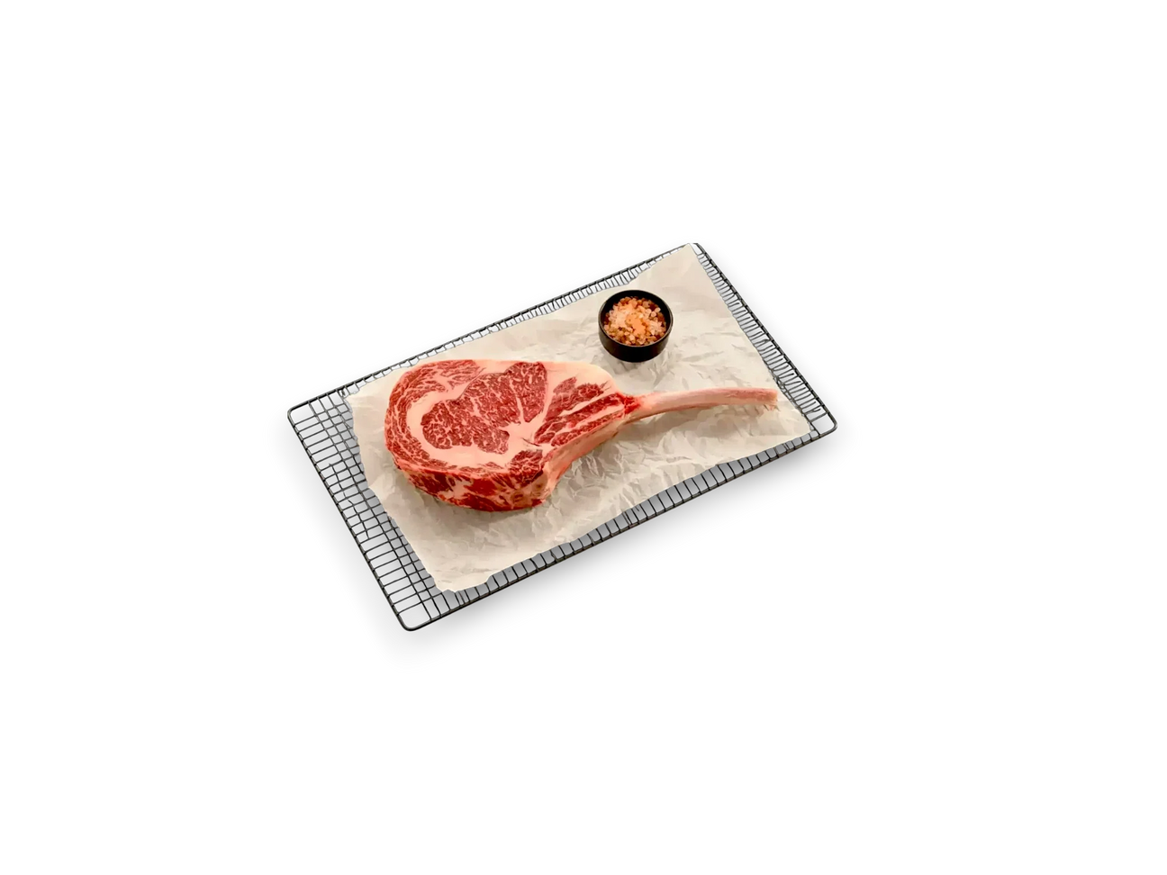 Raw Pure Wagyu tomahawk SB 10 steak with rich marbling on parchment, served with pink salt.