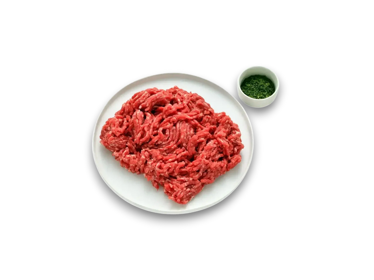 Fresh grass-fed beef mince on a white plate, with chopped herbs in a small bowl, on marble surface.