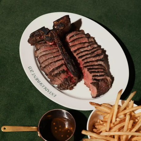 Sliced grilled steak on white plate with fries and sauce, premium Australian beef by Peter Augustus