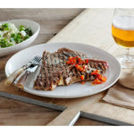 Grilled Australian beef steak with red pepper garnish on plate, served with beer and salad