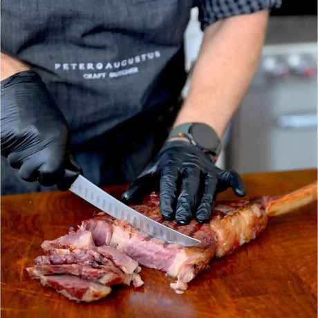 Butcher in Peter Augustus apron slicing premium Australian beef steak