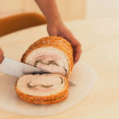 Hand slicing gourmet rolled pork roast from Peter Augustus Craft Butcher on a board
