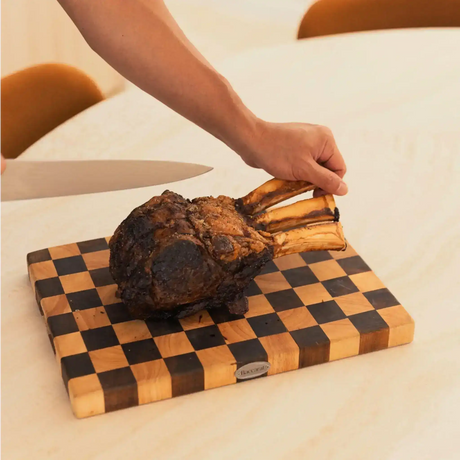 Hand carving a cooked tomahawk steak on a wooden board by Peter Augustus Craft Butcher