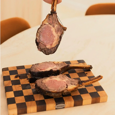Three cooked tomahawk ribeye steaks on a wooden board, Peter Augustus premium beef