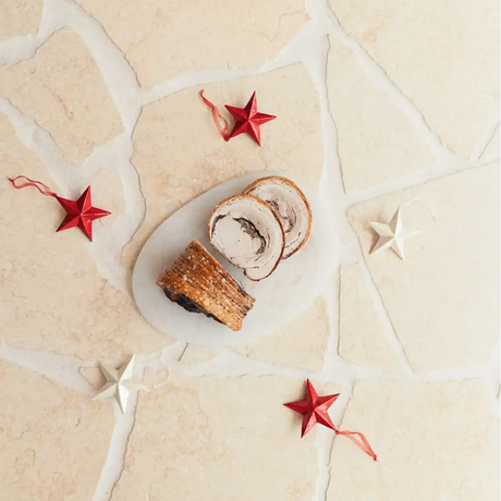 Sliced Australian porchetta on a marble board with red and white festive stars