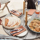 Sliced roast turkey and seasoned potatoes on a wooden table, set for a meal with candles