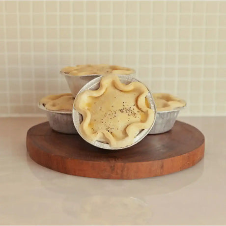 Australian beef meat pies in foil trays on a wooden board, Peter Augustus Craft Butcher.