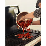 Person grilling premium Australian beef strips with red peppers and onions on a barbecue