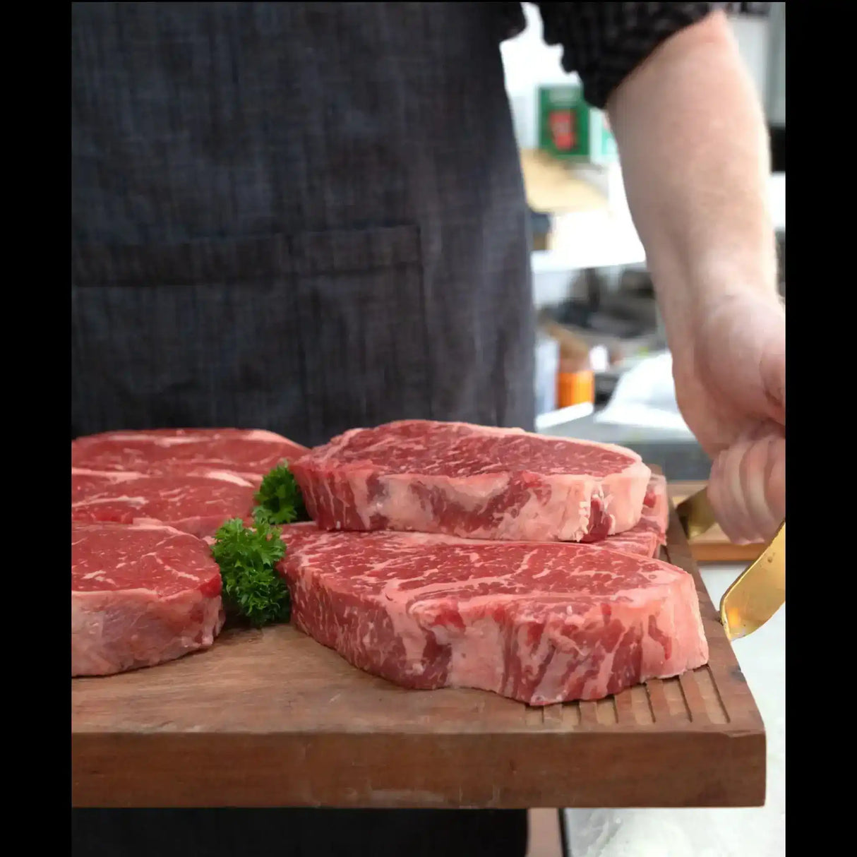 Fresh marbled beef steaks on a wooden board, prepared by a butcher in a kitchen