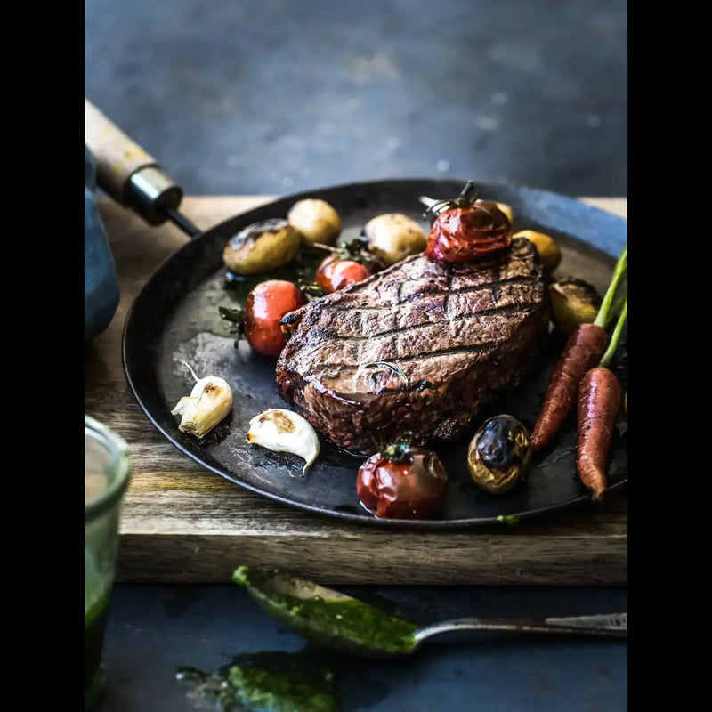 Grilled Australian beef steak with roasted tomatoes, carrots, garlic and potatoes on a plate
