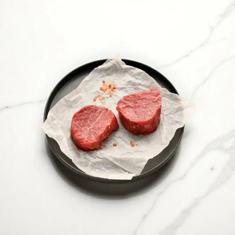 Two raw Angus eye fillet steaks with sea salt on parchment, premium Australian beef