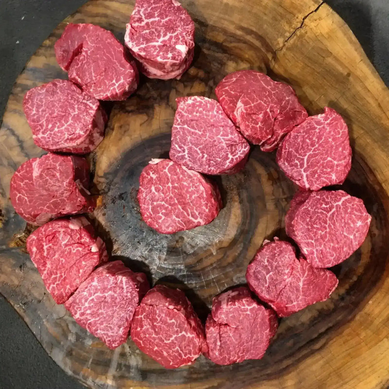 Premium Angus beef tenderloins with rich marbling on a rustic wooden board from Peter Augustus