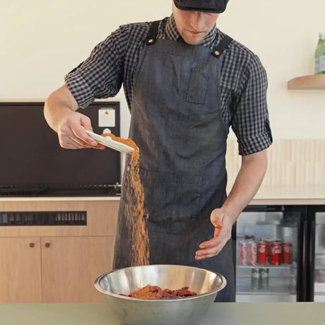 Butcher in apron seasoning premium Australian beef strips in a mixing bowl at Peter Augustus Craft Butcher