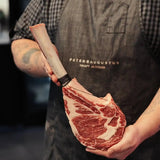Butcher holding premium marbled beef tomahawk steak, showcasing rich marbling and fresh cut