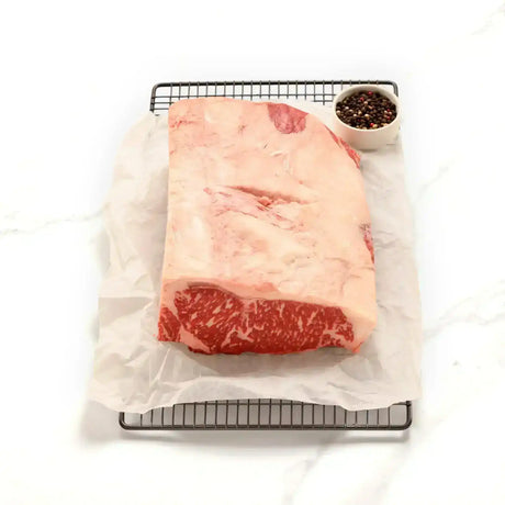 Raw Australian sirloin steak with marbling on parchment paper, peppercorns beside