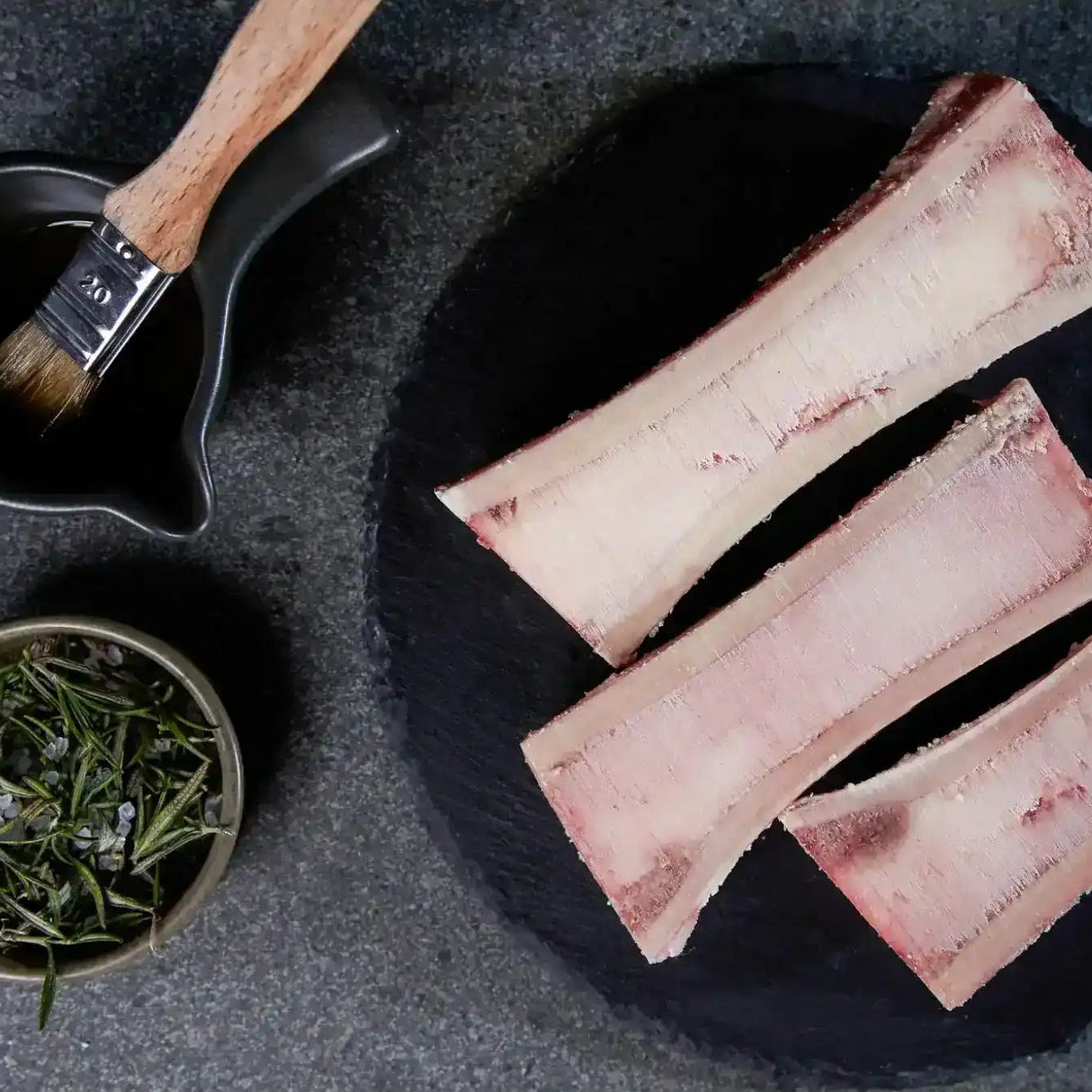 Peter Augustus Australian beef marrow bones with herbs and basting brush on slate plate