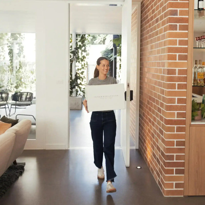 Woman carrying Peter Augustus Craft Butcher gourmet beef delivery box indoors