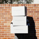 Three Peter Augustus Craft Butcher delivery boxes stacked outdoors against a brick wall