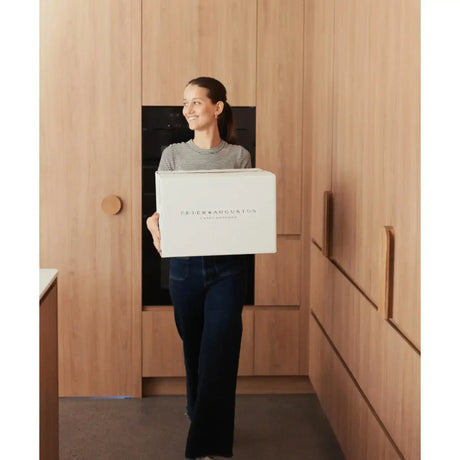 Woman holding Peter Augustus Craft Butcher beef delivery box, smiling indoors