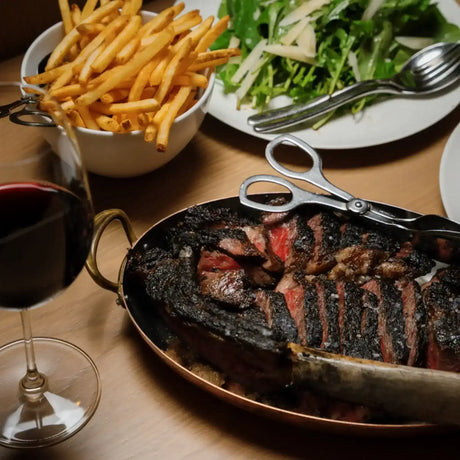 Sliced chargrilled Australian beef steak with fries, salad, and red wine, Peter Augustus