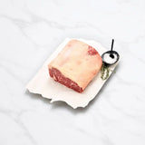 Raw Angus striploin half cut on parchment with salt and herbs on white marble surface