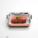 Raw Angus rump roast tied with string and garnished with herbs in a roasting pan