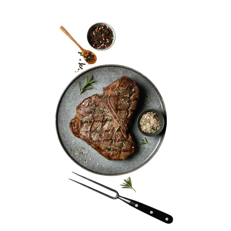 Diamantina Angus T-bone steak on plate with rosemary, seasoning salt, and pepper at Peter Augustus