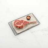 Raw Pure Wagyu tomahawk SB 10 steak with rich marbling on parchment, served with pink salt.