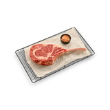 Marbled Wagyu tomahawk steak on wire rack with pink salt, fresh grass-fed beef cut