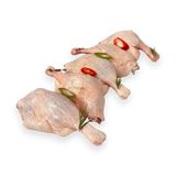 Two raw duck legs with red peppers and green herbs